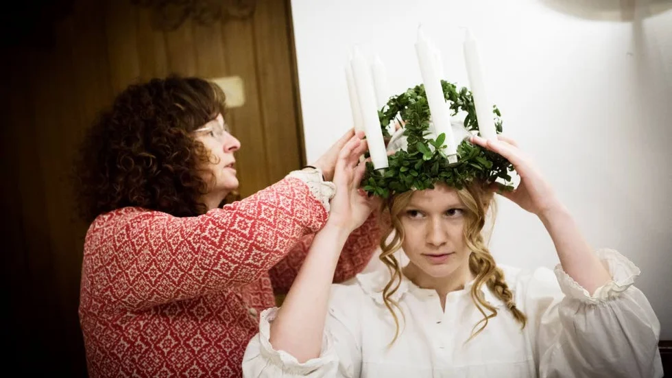 Lucia Ellen Broström får hjälp av mamma att få luciakronan på plats.