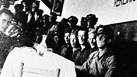Svenskar i Valencia hösten 1937. Trea från höger är Sven Brännström som lydde under en sovjetisk officer, L.A. Ejtingon. Elof Abrahamsson sitter till vänster om honom. Längst t.v. Per Eriksson. Under skylten på tyska, Proletärer i alla länder - förena er.
