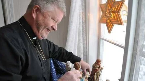 Kyrkoherden Sixten Klemetz gör i ordning i vardagsrumsfönstret hemma i Öregrunds prästgård.