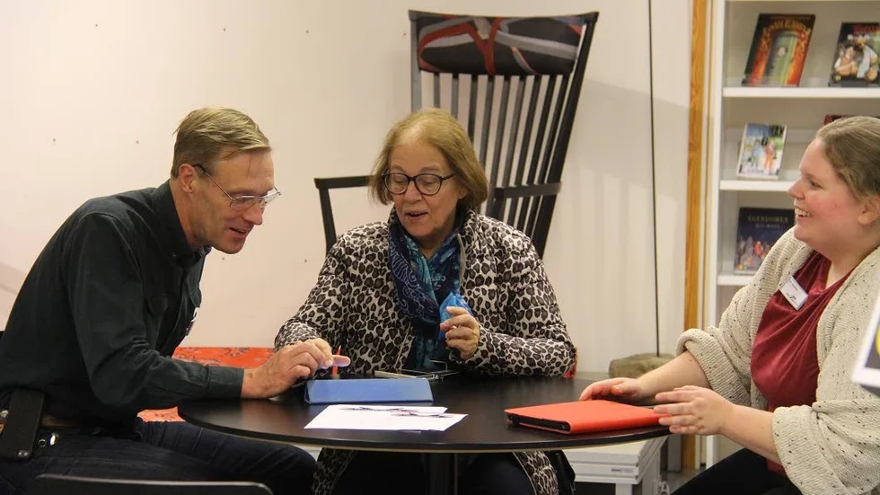 Lars Malmsten och Sofia Wirström på Håbobiblioteket hjälper Elisabet Åström att hitta de bilder som hon vill skicka i väg med ett mejl.