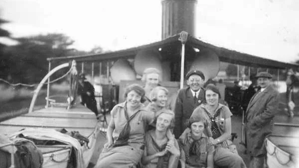 Juli 1925. Astrid Ericsson och fem kamrater vandrar in i Östergötland. Här på väg hemåt, med båten Pallas mot Bergs slussar. Männen är tyskar som kvinnorna träffat på båten.