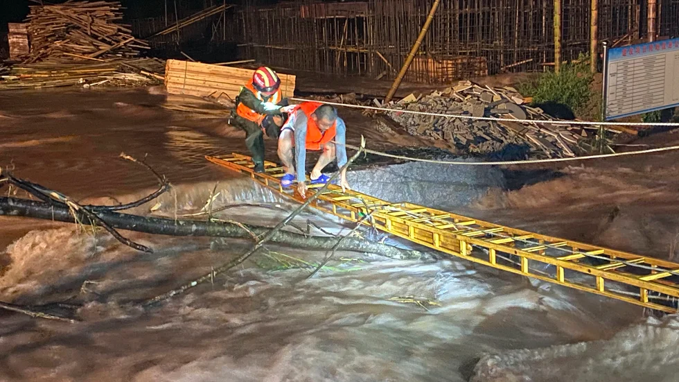 En räddningsarbetare hjälper en man att korsa ett översvämmat område i den kinesiska provinsen Jiangxi.