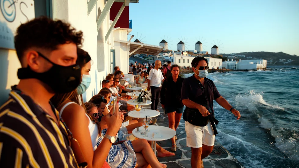 Turister på grekiska Mykonos beundrar solnedgången över Egeiska havet 16 augusti 2020.