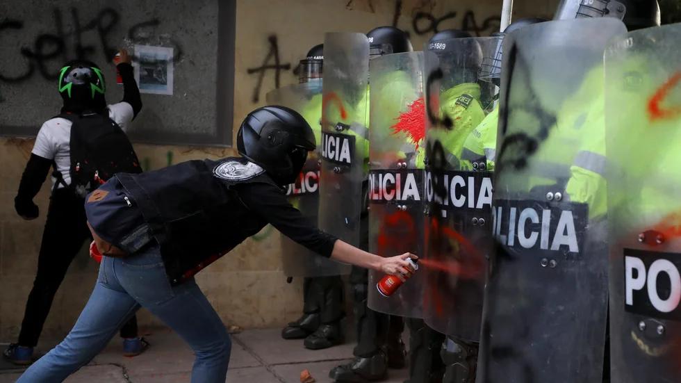 En demonstrant sprayar färg på kravallpolisernas sköldar i Bogotá.