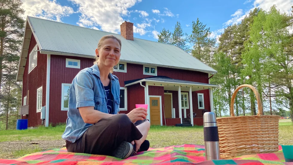 Johanna Borgenstål picknickar på filten framför sitt konsteldorado i Backträsk gamla byaskola.