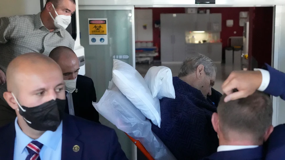 Milos Zeman (med hängande huvud till höger) på väg in på sjukhuset UVN i söndags.