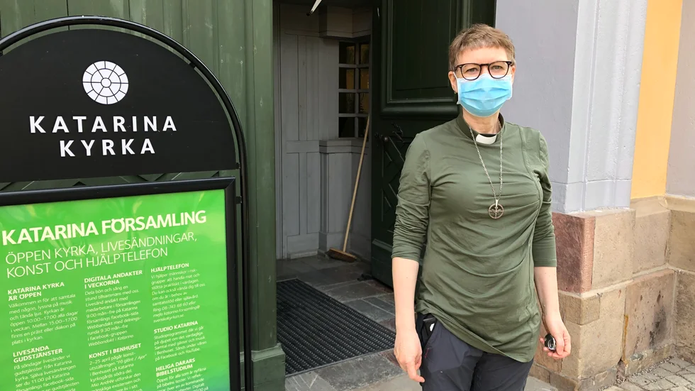 Kikki Högdahl, diakon i Katarina församling, har munskydd på och besöksräknaren till hands när hon välkomnar besökarna åter till gudstjänst i Katarina kyrka i Stockholm.