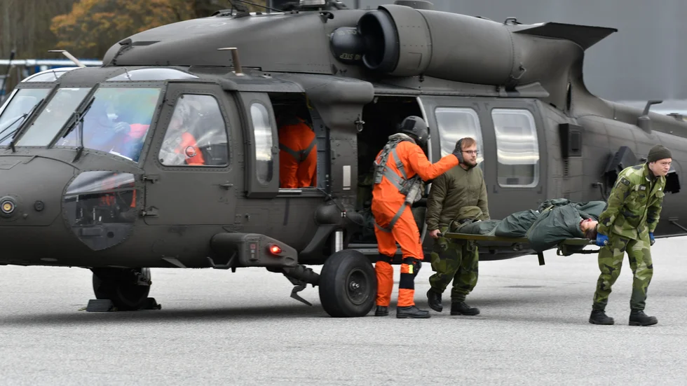 En fingerad skadad har hämtas upp i Stockholms skärgård och lämnas här av vid förbandsplats av en helikopter 16. När man flyger över vatten har besättningen särskilda isoleringsdräkter. 