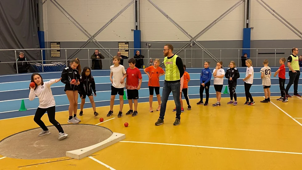 Motala AIF:s Melissa Basic, tio år, stöter kula under överinseende av funktionären Pierre Axén. Basic hoppades på personbästa i kula i Team Sportia-spelen som lockade 180 deltagare till Vätternrundan arena på söndagen.