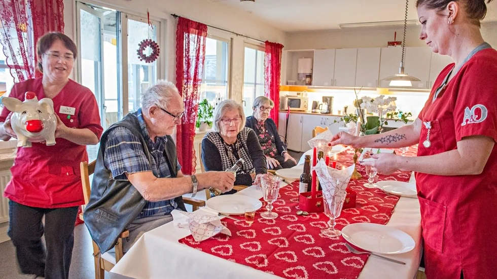 Eva Carls Malmström dukar fram en julgris av porslin och Kattis Ericson tänder ljusen. Lars Reinholdson, Kerstin Reinholdson och Elvy Johansson ser fram emot nubbe och mat.