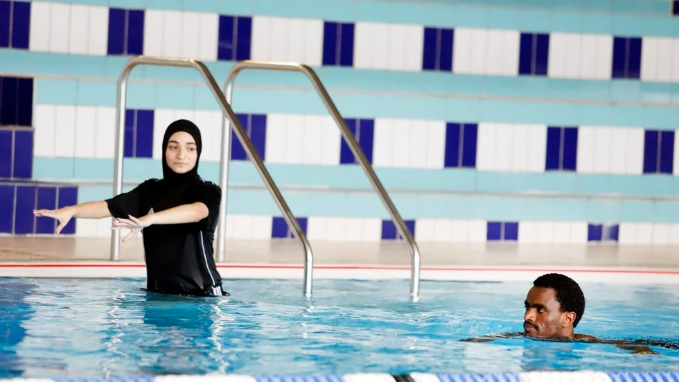 Simtränaren Sarab Al-thaie instruerar Aklilu Begatsion i Thomasbadet under lördagens föreningsmatchning för nyanlända.