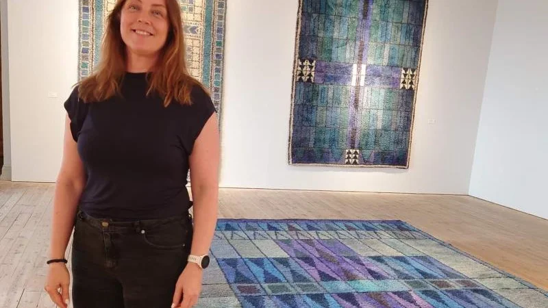 Åsa Törnblom, intendent vid Uppsala slottsmuseum, intill Luleå domkyrkoförsamlings kormatta "Midnattssol", skapad av textilkonstnären Ingrid Skerfe-Nilsson.