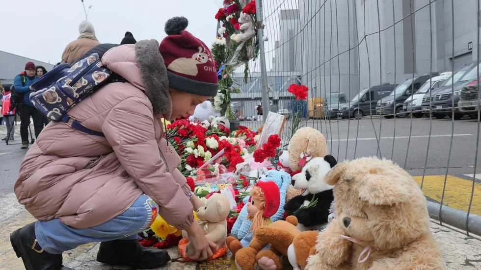 Ett barn lämnar en nalle vid ett stängsel som omgärdar byggnaden där över 130 personer dödades av kamouflageklädda män med automatvapen på fredagskvällen.