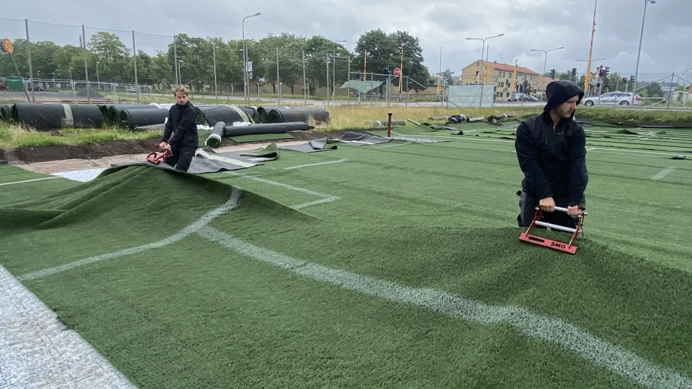 Här sträcks det nya konstgräset på Fålhagens IP ut. När det sträckts ut ska kanterna på de olika delarna av gräset limmas ihop. Därefter ska 72 ton finkornig sand strös ut på gräset.