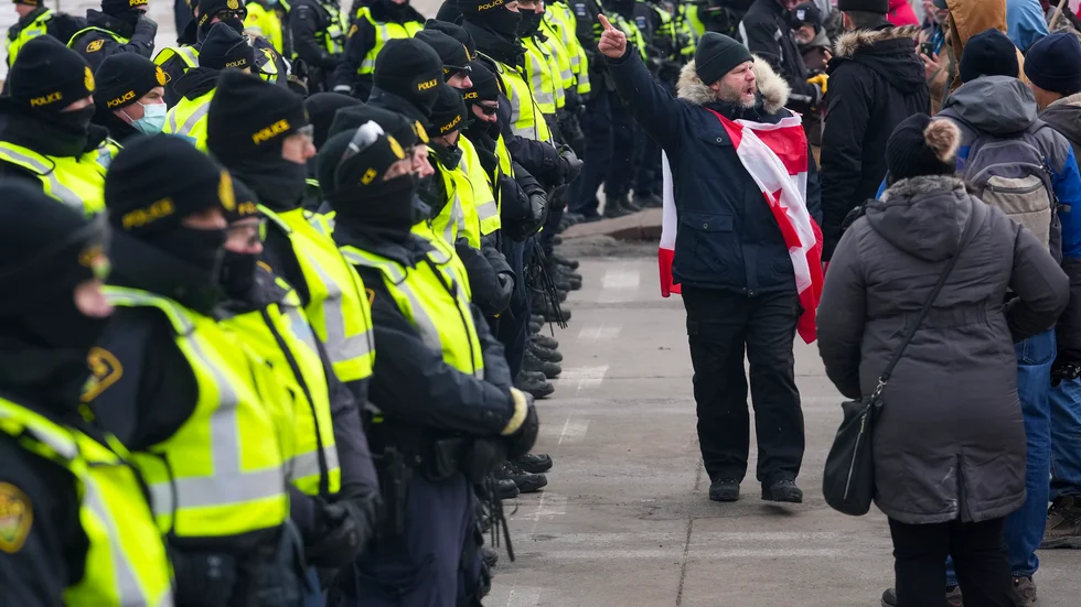 En demonstrant skriker till de kanadensiska poliserna samtidigt som andra demonstranter gör sig redo att lämna Ambassador Bridge, som går mellan Detroit i USA och staden Windsor i Kanada.