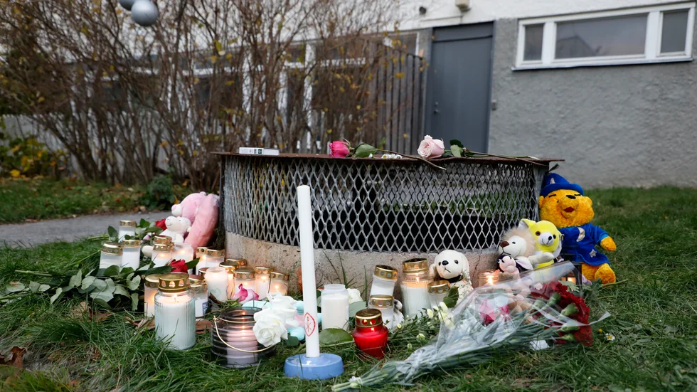 Gosedjur, blommor och ljus har lagts ner vid den plats där två barn hittades med livshotande skador utanför ett bostadshus i Hässelby i söndags kväll. Ett av barnen avled senare av sina skador. Tillståndet för det andra barnet är fortfarande allvarligt.