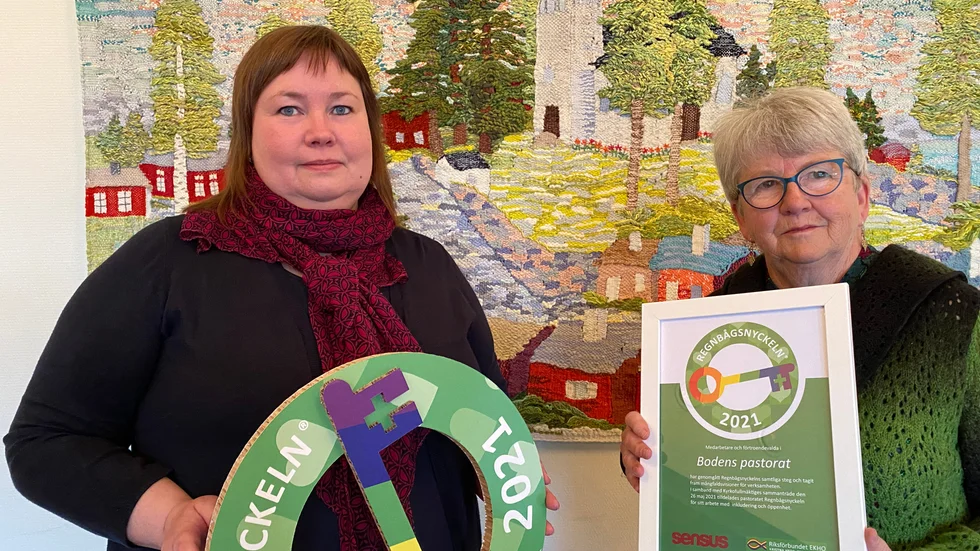 Kyrkofullmäktiges vice ordförande Erika Sjöö och ordförande Birgitta Mörk tar emot Regnbågsnyckelmärkningen för Svenska Kyrkan Boden.