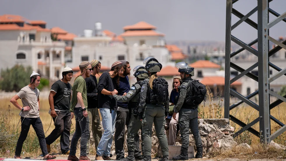 Israeliska soldater stoppar bosättare från att ta sig in i ett palestinskt samhälle på Västbanken. Bilden är från i onsdags.