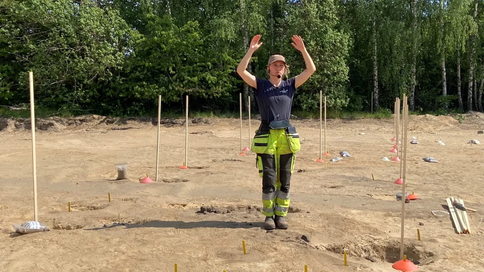 "Här står jag mitt i ett bronsåldershus", säger Linnea Hernqvist, arkeolog och dagens guide. Pinnarna visar var väggarna stod på 1000-talet före Kristus.