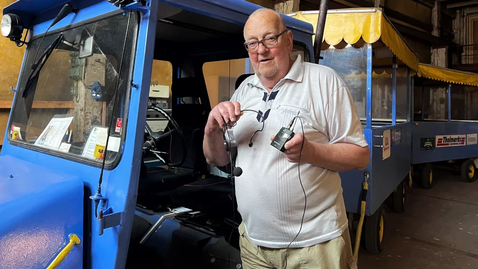 Göran Forslund med mikrofonen som tåget är utrustad med. Det sitter högtalare i taket för att passagerarna ska kunna höra den guidande rösten.