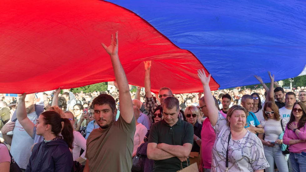 Demonstranter håller upp den serbiska flaggan under en massprotest mot regeringen i huvudstaden Belgrad på lördagen.