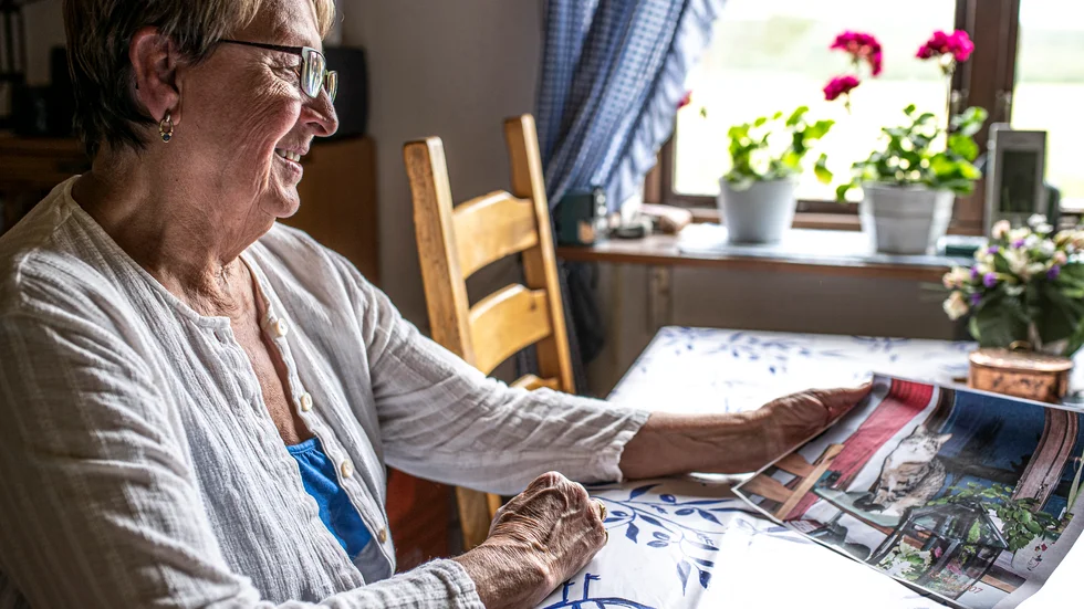 Inger Ögren tittar på bilder med Mio från förr, i ett tidigare reportage om den ålderstigna kissen från 2019. 