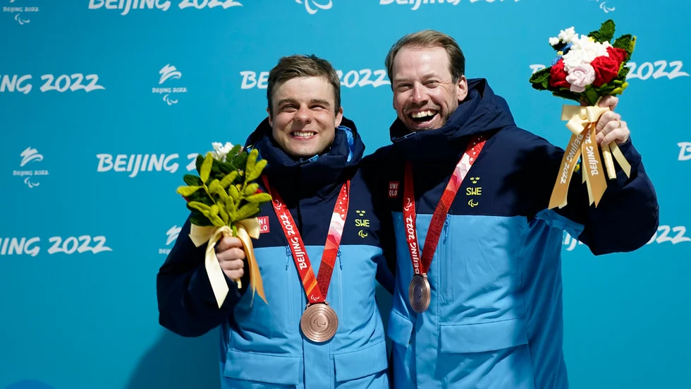 Zebastian Modin och hans ledsagare Emil Jönsson Haag vid medaljceremonin efter bronset i skidsprinten.