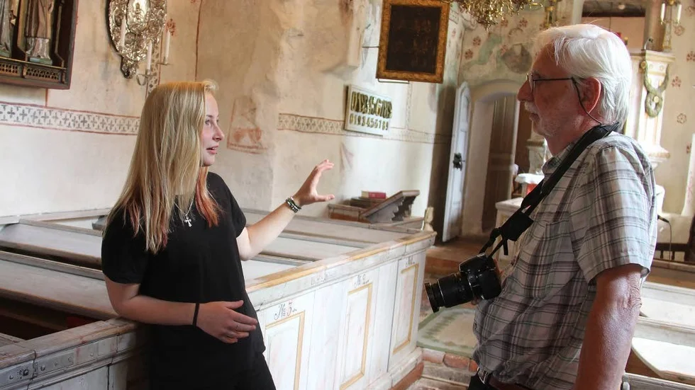 Sommarguiden Jonna Randen i Yttergrans kyrka svarar på frågor från kyrkoturisten Lars Lindgren, som besökt flera kyrkor på sin dagsutflykt.