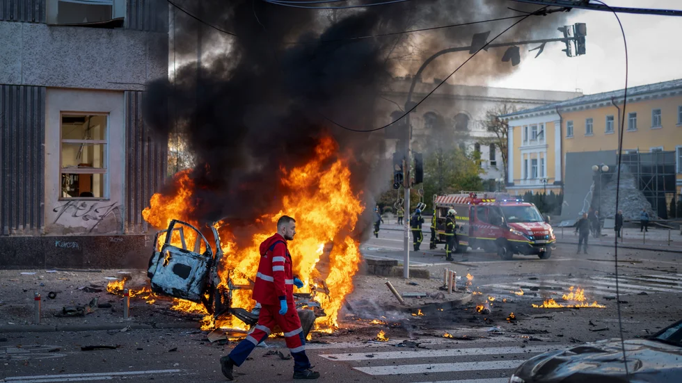 En räddningsarbetare går förbi en brinnande bil efter de ryska attackerna mot Kiev.