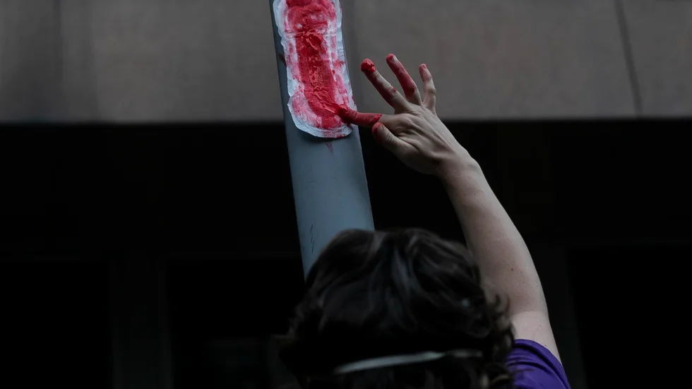 En blodig binda äcklar och provocerar. Här smetar en kvinna röd färg på en binda vid en protest mot Brasiliens president Jair Bolsonaro. Arkivbild.