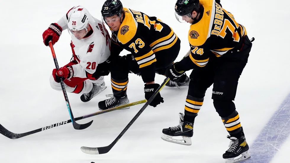 Carolinas Sebastian Aho i kamp om pucken med Bostonspelarna Charlie McAvoy (nummer 73) och Jake DeBrusk (74).