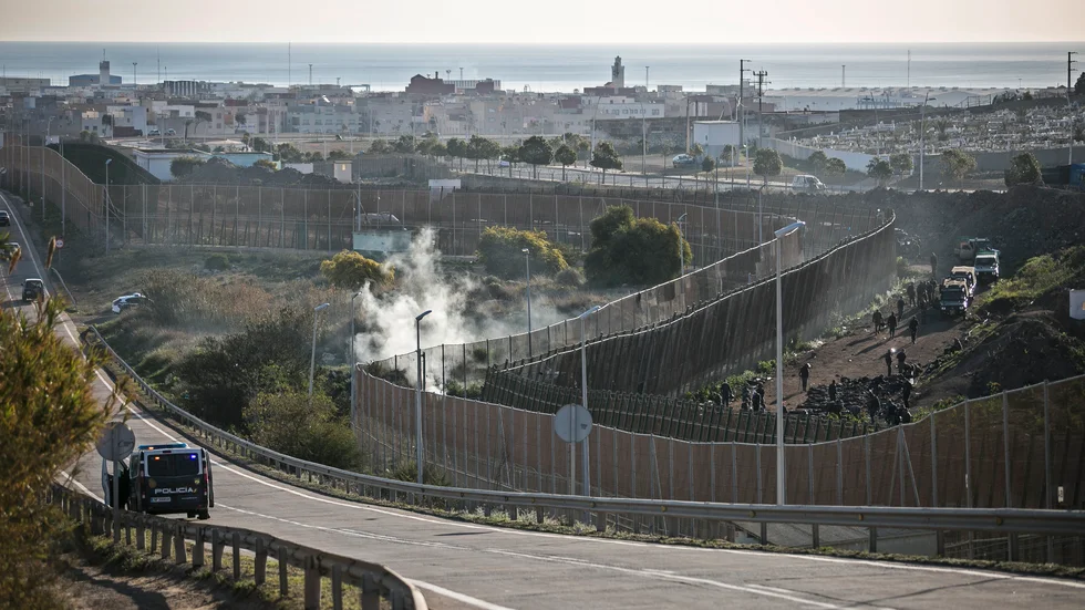 Marockanska säkerhetsstyrkor stoppar migranter från att ta sig över stängslet som skiljer Melilla från Marocko . Bilden är tagen i mars i år.