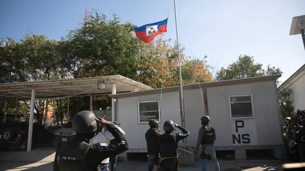 Poliser gör honnör vid Haitis flagga som halats på halv stång i Port-au-Prince.