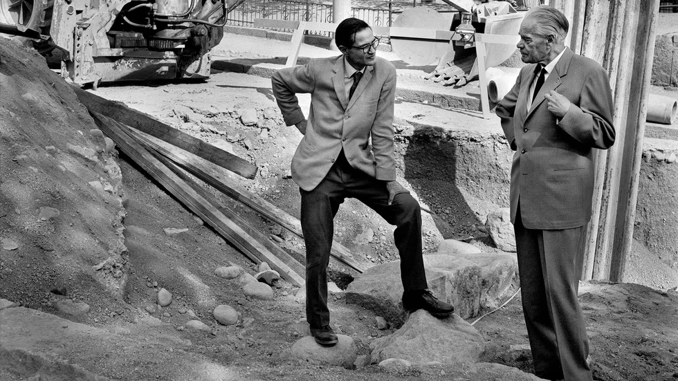 Jan Fridegård, till höger, i samspråk med stadsbibliotekarie Thore Floderus vid ett gatuarbete på Kyrkogatan i Enköping. Året är 1965. Chattboten verkar inte veta vem Jan Fridegård var.