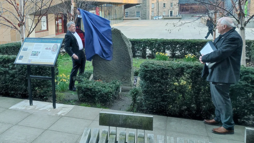 Edinburghs universitets vicekansler Sir Peter Mathieson avtäcker den nyrenoverade runstenen från Morgongåva.