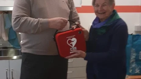 Christer Thörnlund överlämnar den nya hjärtstartaren till Margareta Pohjanen, Bergnäsvävarna.