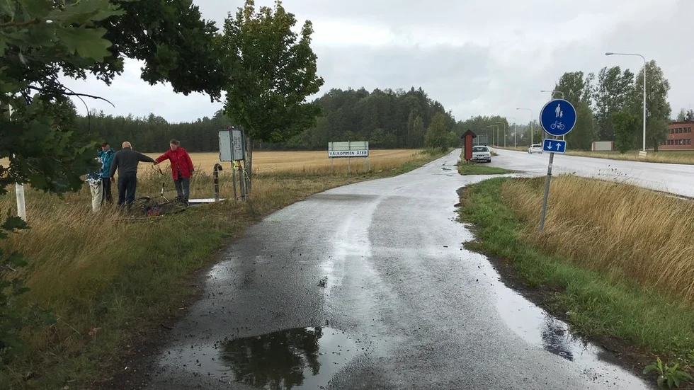Samling i regnet vid informationsskylten vid infarten till Trosa där en ny infart ska byggas, enligt planerna.