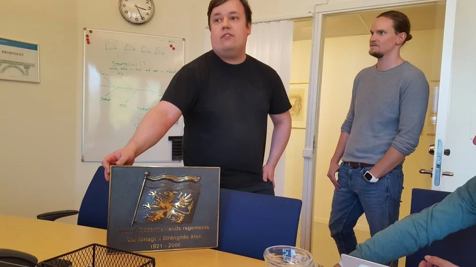 Mathias Hällqvist och Kristoffer Verner från plan-och byggenheten visar upp tavlan från P10 som tidigare i veckan hittades i kommunens arkiv.