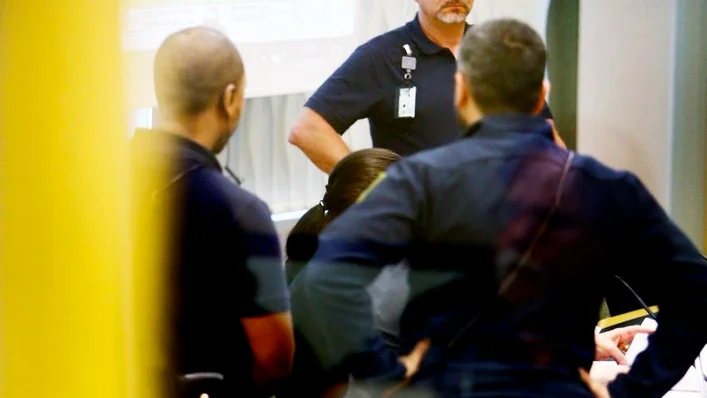 En ring runt den mordmisstänkta 42-åringen. Efter att åklagaren fått klart för sig att 42-åringen skickat meddelanden till omvärlden via pressfotograferna var det på onsdagen en stadig mur av häktesvakter runt henne så fort dörren öppnades.
