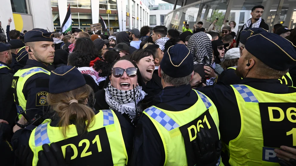"Polisens förberedelser vittnar även om hur allvarlig hotbilden var. Helgens polisinsats var en av de största i Sveriges historia." skriver Edvard Hollertz om Eurovision i Malmö. På bilden en grupp demonstranter som möttes av en mur av poliser utanför Malmö Arena.