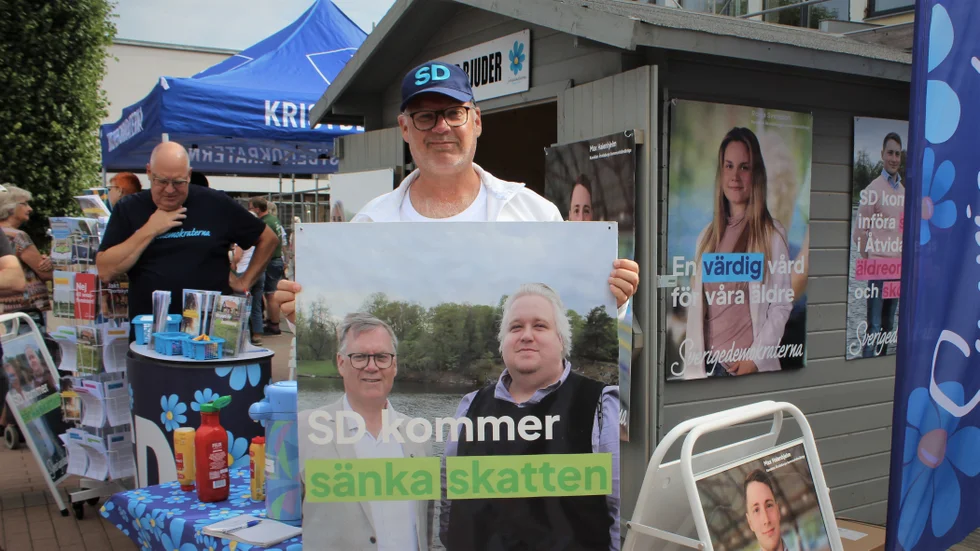 Jan Svensson (SD)  håller upp en av SD:s valaffischer. Den rymmer ett konkret vallöfte om att SD ska sänka skatten. På frågan när det kan ske, svarar Svensson: Tidigast 2024.
