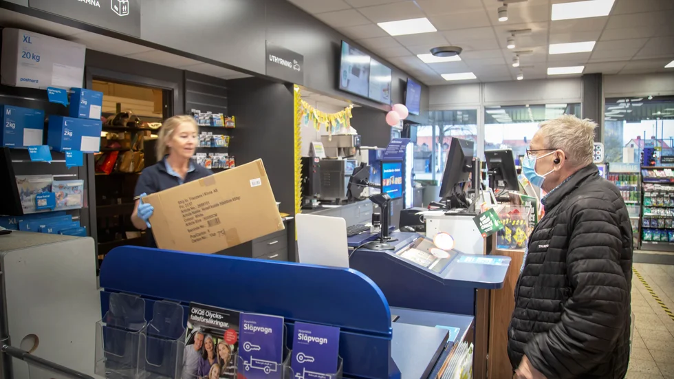 Britt Johansson lämnar ut ett stort paket till Åke Jansson vid OK/Q8 i Visby. "Det har varit jättemycket mer att göra ända sedan pandemin bröt ut", säger hon.