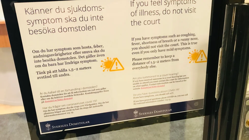 Redan på väg in i trapphuset till tingsrätten i Eskilstuna uppmanas besökarna att inte komma in om de känner några sjukdomssymptom.