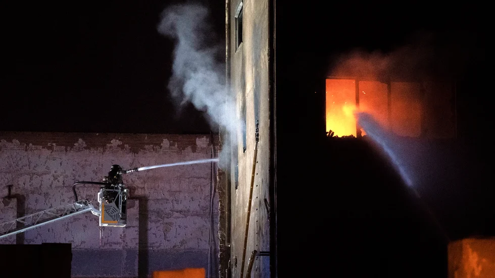 Brandmän arbetar för att släcka lågorna i en lagerbyggnad i Badalona i Spanien, där många migranter sökt skydd.