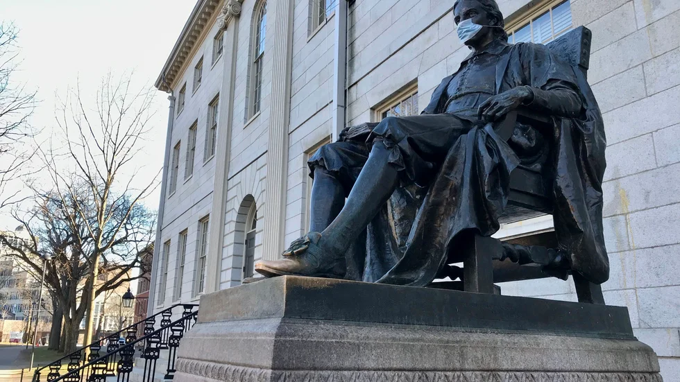Den välkända John Harvard-statyn på universitetets campus i Cambridge har också fått ett munskydd. Arkivbild.