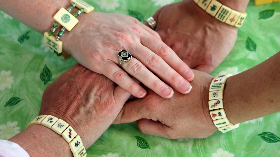This May 31, 2013 photo shows women displaying bracelets made of mahjong pieces during a game night gathering in Mayfield Village, Ohio. For the baby boomer generation, getting together to play games is a way to stay active and social. It also can help people stay mentally sharp. (AP Photo/Bonnie Gruttadauria)