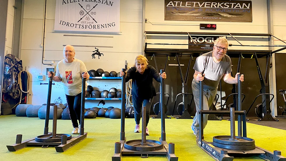 Ulla Borgström, 72, Ulla Luoto Karlsson, 68, och Sven Björklund, 68, trycker släde med olika tyngder på. De deltar i den seniorgrupp på Atletverkstan som körs på prov, med lite tuffare träning och fokus på kroppens grundläggande rörelser.