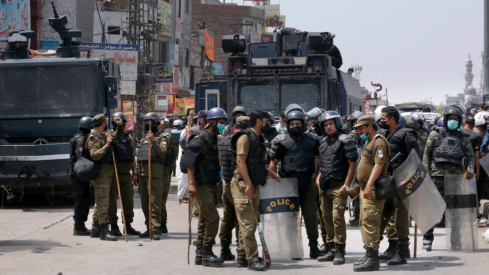Poliser samlas efter sin insats vid de våldsamma protesterna i söndags i Lahore.