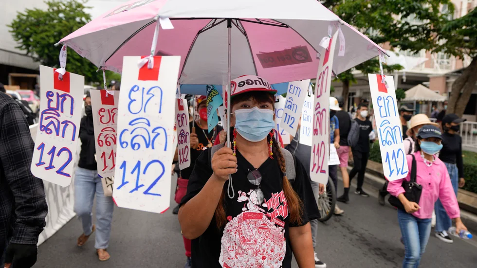 En prodemokratisk demonstrant bär skyltar med texten "nej till artikel 112", den avdelning av Thailands brottsbalk som handlar om majestätsbrott.