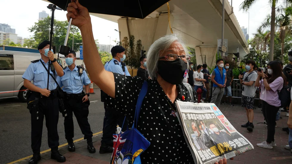 En demokratiaktivist med ett exemplar av Apple Daily utanför en domstol i Hongkong.